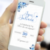 Lembrete de casamento azul exibido em um celular, com arranjos florais em tons de azul no topo e no rodapé, nomes dos noivos em destaque, data e horário organizados de forma elegante.