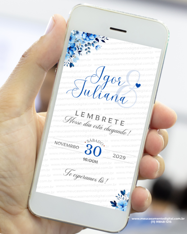 Lembrete de casamento azul exibido em um celular, com arranjos florais em tons de azul no topo e no rodapé, nomes dos noivos em destaque, data e horário organizados de forma elegante.
