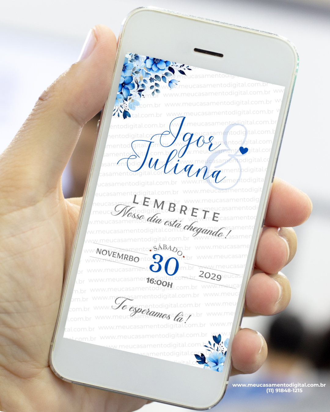 Lembrete de casamento azul exibido em um celular, com arranjos florais em tons de azul no topo e no rodapé, nomes dos noivos em destaque, data e horário organizados de forma elegante.