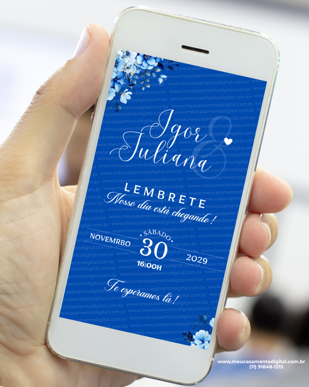 Lembrete digital de casamento em fundo azul intenso exibido em um celular, com flores azuis nos cantos, nomes dos noivos em caligrafia elegante e informações do evento organizadas ao centro.