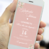 Lembrete digital de casamento em tom rosé exibido na tela de um celular, com flores delicadas nos cantos, tipografia elegante com os nomes do casal e data do evento em destaque.