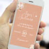 Lembrete digital de casamento rosé gold exibido em celular, com fundo em tom rosé, flores delicadas nos cantos, nomes do casal em caligrafia elegante e data do evento em destaque.