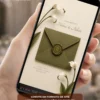 Convite de casamento verde oliva com copo de leite, envelope digital elegante e flores delicadas exibidos na tela de um celular.